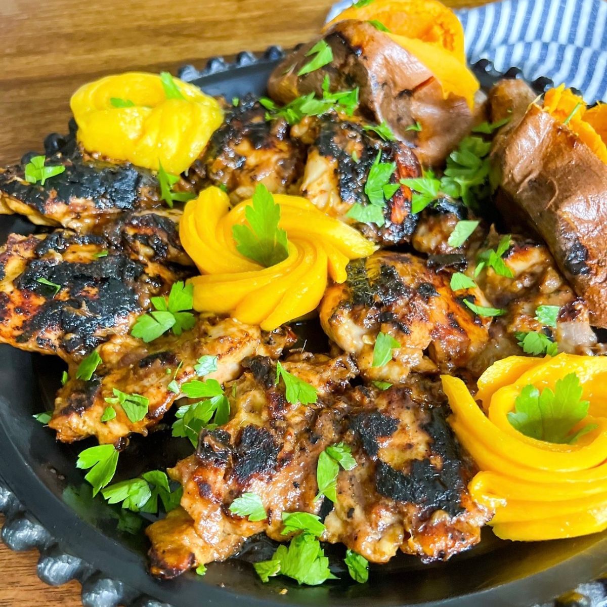 grilled mango chicken on black round plate