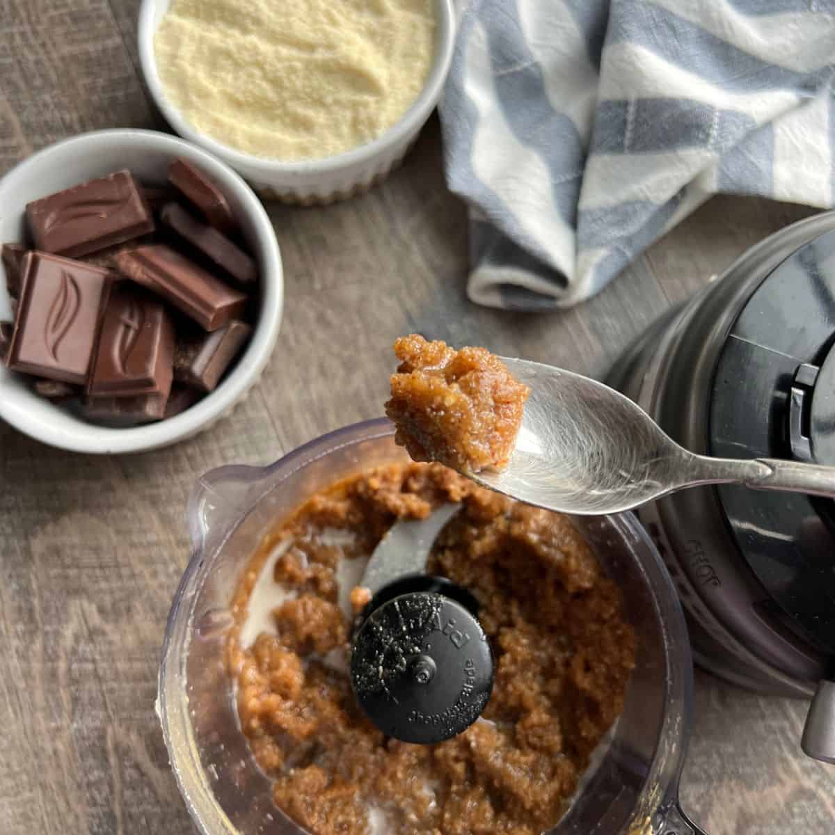 A food processor filled with blended nut butter, maple syrup, pecans and coconut oil to make a crumbly base.