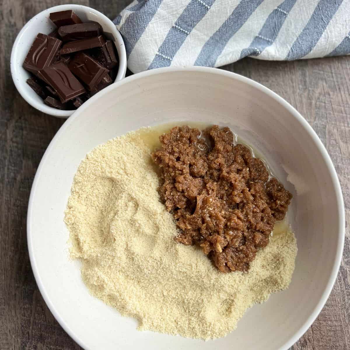 The nut butter base is added to a bowl in preparation of kneading the ingredients together. There is a smaller white bowl of chocolate squares included too.