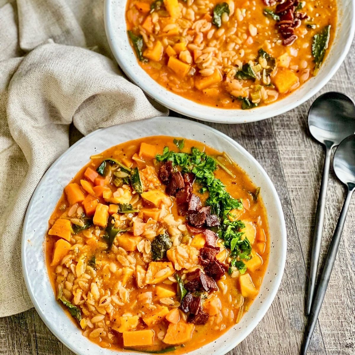 Autumn Minestrone Soup in round white bowl with 2 black spoons