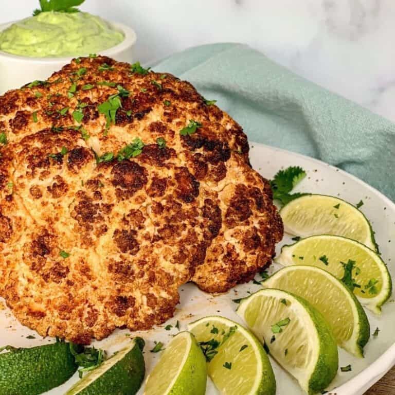 taco cauliflower & avocado lime crema on round white plate with lime slices