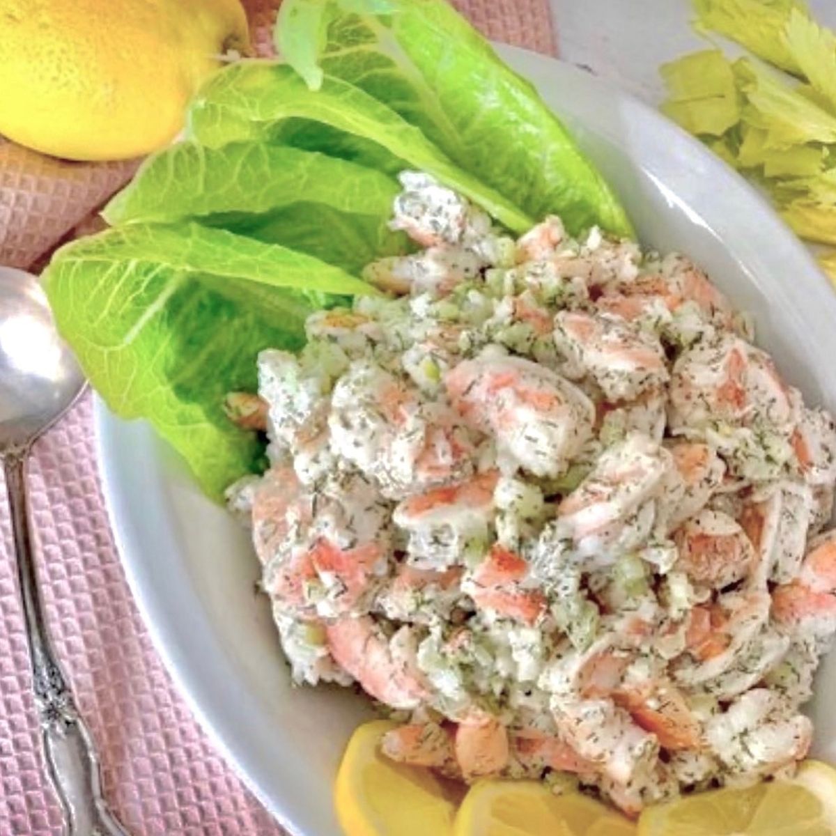 shrimp salad in oval white bowl with romaine and lemons