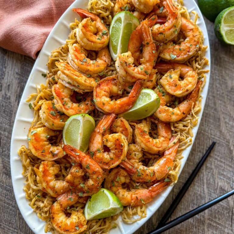 cajun shrimp on oval white plate with limes