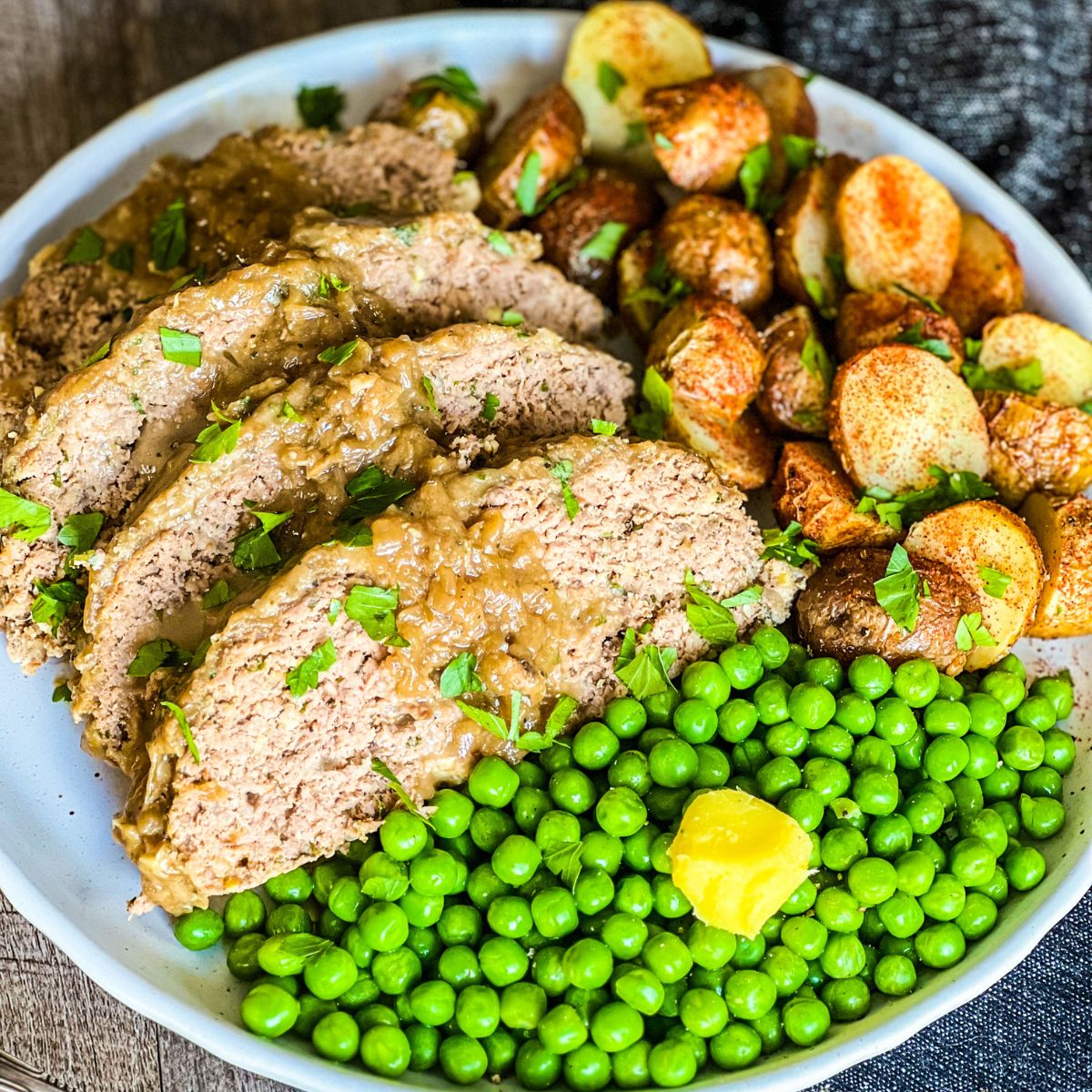 french onion meatloaf on round plate with peas and potatoes