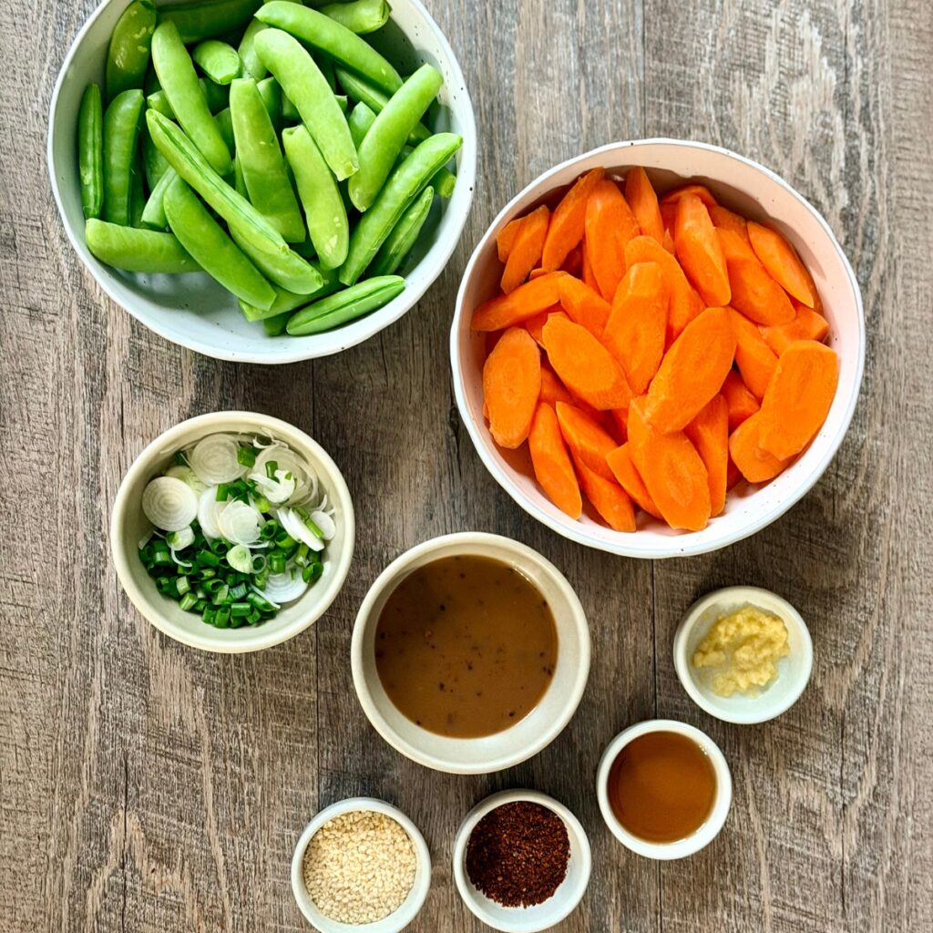 ingredients consist of carrots, sugar snap peas, scallions, ginger, sesame oil, teriyaki sauce, Gochugaru (Korean Chili Pepper Flakes) and sesame seeds