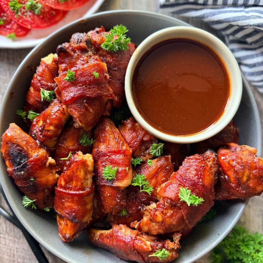 bacon wrapped chicken wings with tangy sweet and spicy bbq sauce with extra bbq sauce for dipping