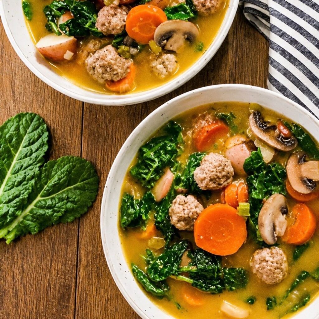 sausage meatball soup with bite sized meatballs, potatoes, carrots, mushrooms and kale in a creamy broth