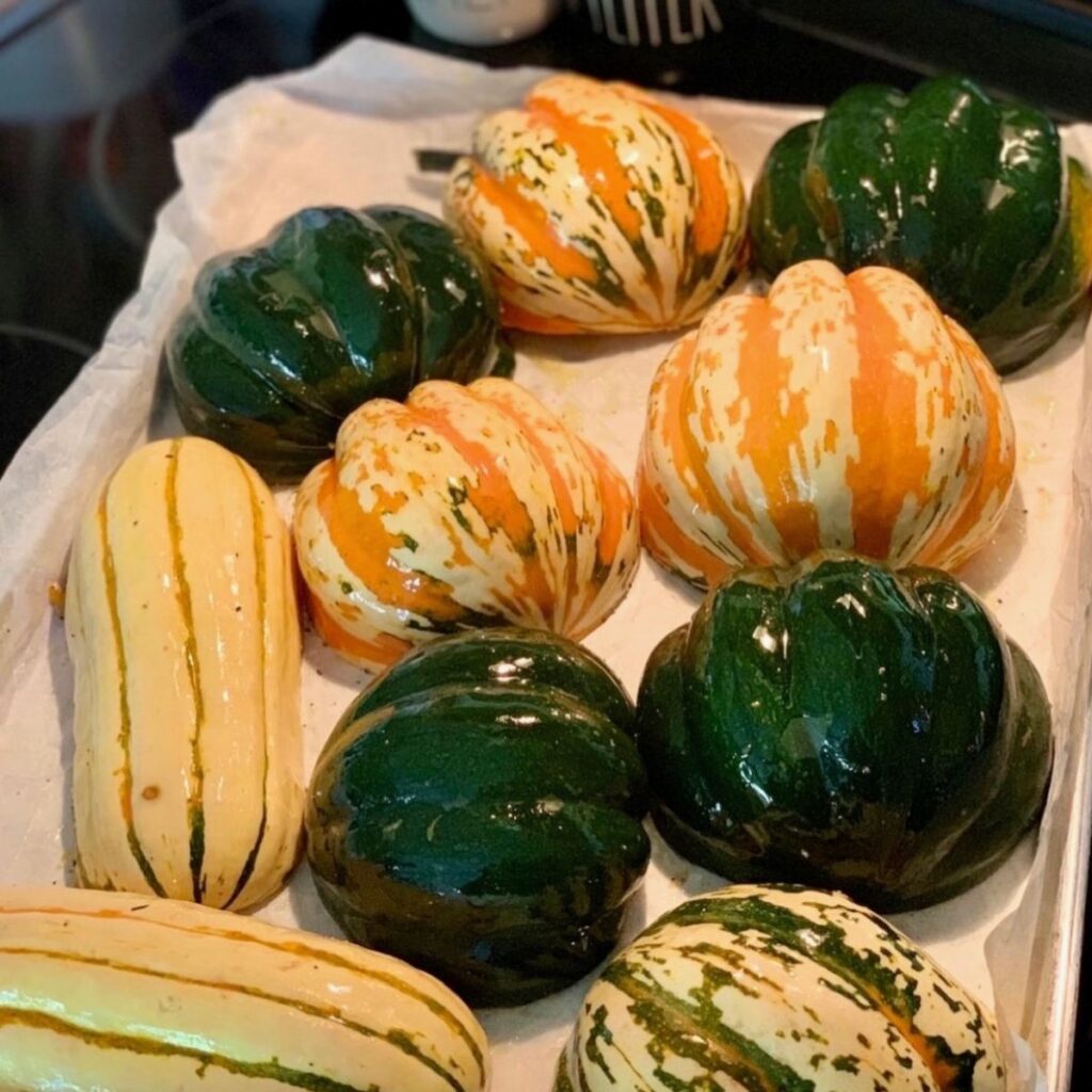 variety of squash cut in half cut side down on baking sheet drizzled with olive oil