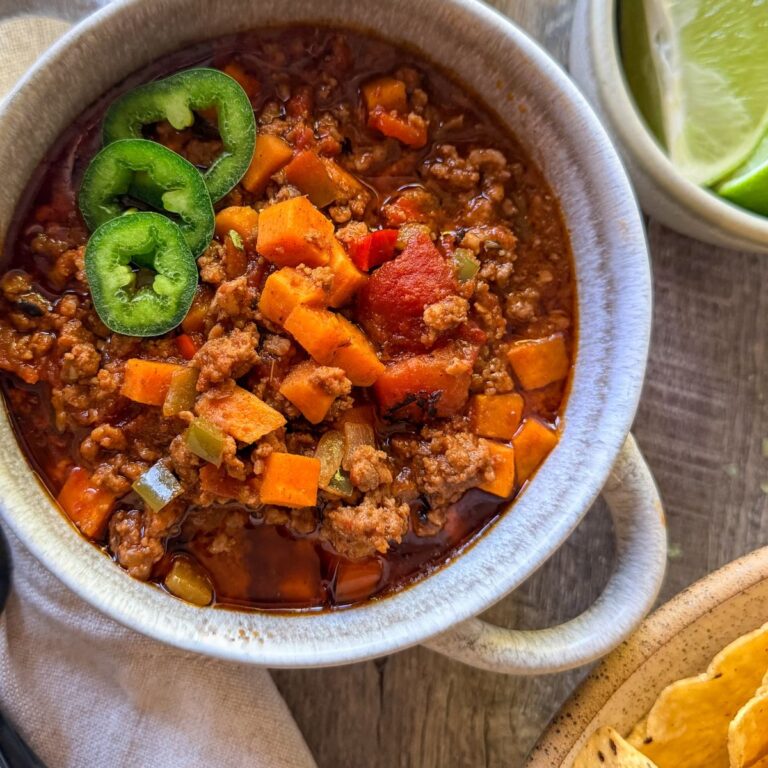 whole30 chili with jalapeño slices in round bowl with handles - lime wedges and tortilla chips on the side