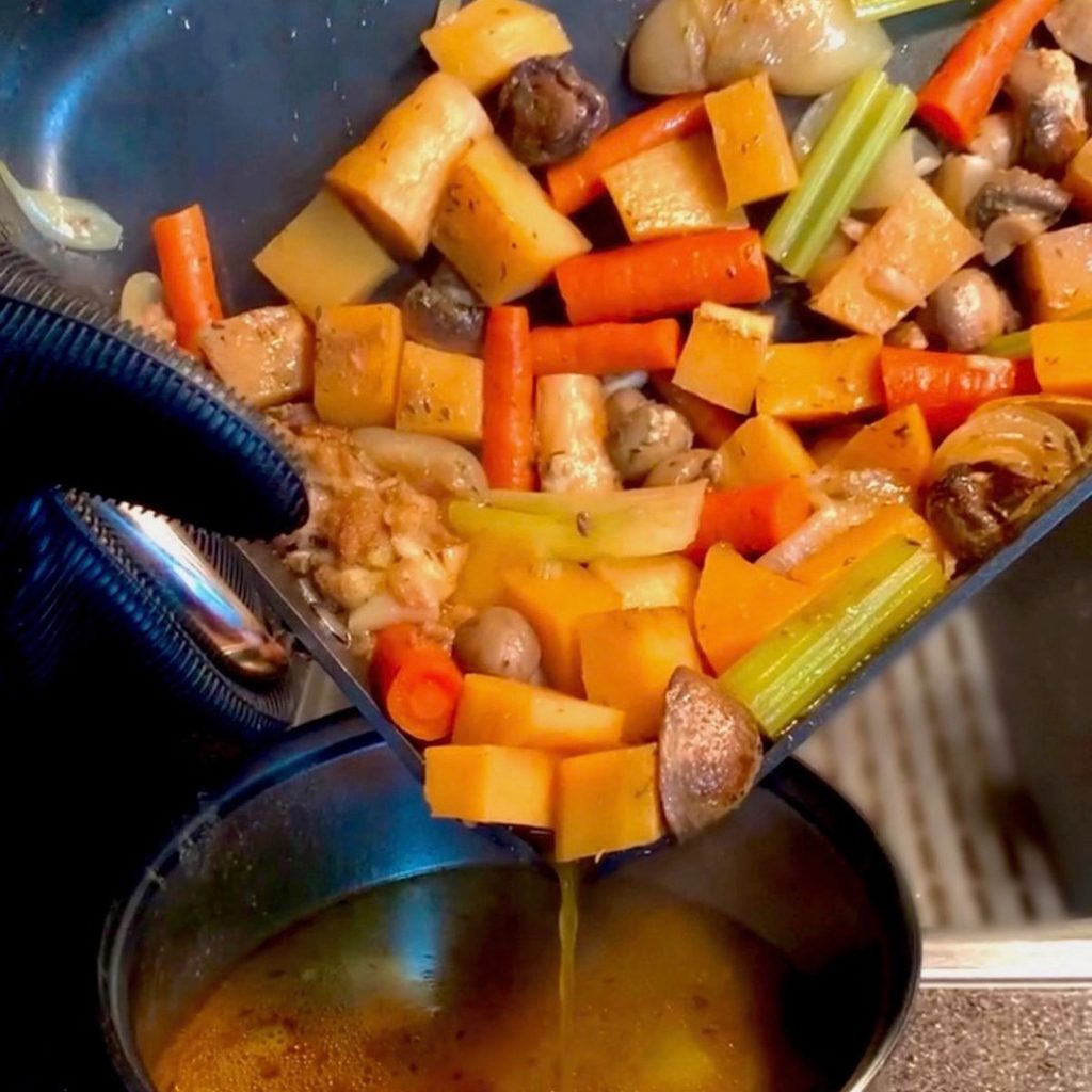 veggie gravy all the veggies in a roasting pan being poured into a saucepan